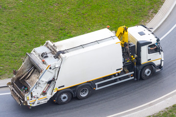 Large garbage truck to transport household waste travels along the city highway, aerial view.