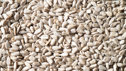Scattered peeled sunflower seeds as background. Shelled sunflower seeds texture. Top view sunflower seeds closeup