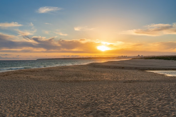 Landscape of beautiful sunset on the ocean, with sand, horizon with a blue sky. Portugal.