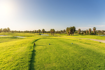 Beautiful, with green grass, golf course, with a pond, with sunny blue and clear sky. Portugal,...