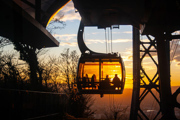 Ski lift silhouette with people inside and beautiful orange sunset at the background.  Funicular...