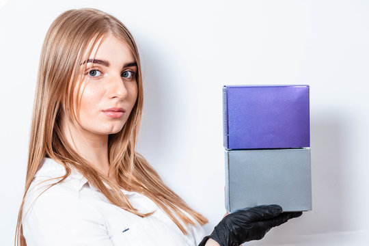 Portrait Of A Blonde Woman On A White Background. Girl In A Black Glove. Girl Holding Small Cardboard Boxes. Free Space For Text.