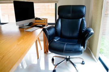 Wooden dining table with black working chair,mornitor near window, adapt as working area to work from home avoid corona virus.Social distancing and stays at home safe from COVID-19 infection.