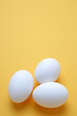 Eggs,Three White egg on the yellow background in center,Copy space for the ads