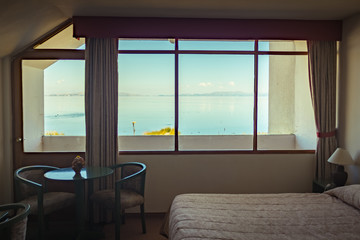Single Bedroom with Large Windows Overlooking Lake Titicaca with Celestial Waters and Mountains in the Background in Puerto Perez, La Paz / Bolivia