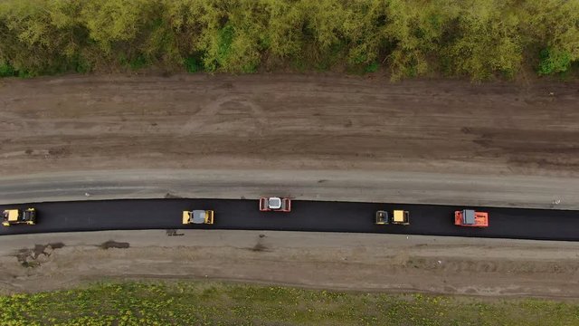 Roller machines make new asphalt roads. The asphalt paver squeezes hot asphalt.