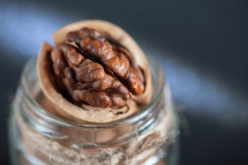 Fresh tasty walnuts in a jar close-up with beautiful bokeh in the background.