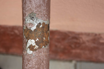 A haggard old pipe against a stucco wall has damaged a wall in the industrial part of the city with water. The concept of repair of heat pipes
