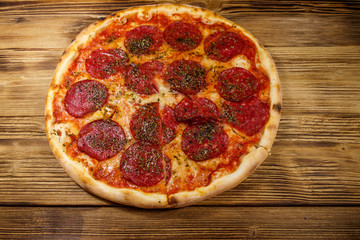 Delicious fresh pizza with sausage and cheese on a wooden table