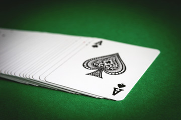 A deck of playing cards laid out on a green table. Top card ace of spades.