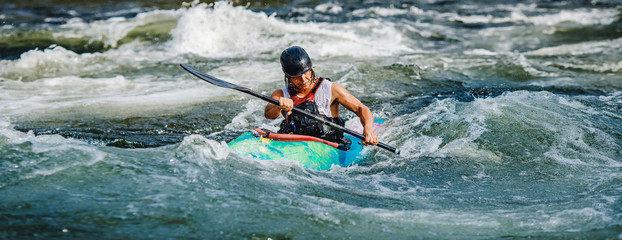 Guy in kayak sails mountain river. Whitewater kayaking, extreme sport rafting
