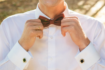 Groom ties a brown bow-tie