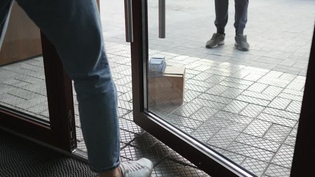 A woman picks up a parcel at the front door. The courier delivers the parcel to the door.