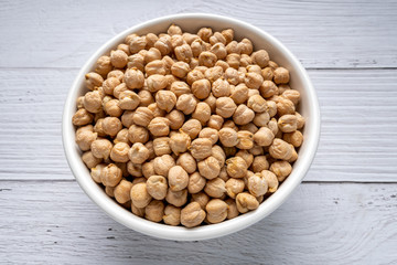 Uncooked dried chickpeas in bowl on white wooden table. Heap of legume chickpea background. top view. vegan food concept