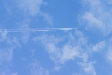 the plane flies among the clouds against the blue sky, leaving a trail behind it. The concept of ending the coronavirus pandemic and increasing air travel.