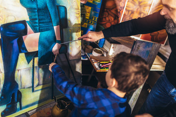 Father and son working and painting together in art studio