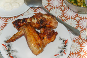   cooked on fire, chicken wing and drumstick on a plate next to mayonnaise and salad   