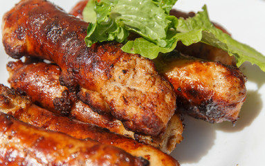   cooked on fire small sausages close-up in a white plate   