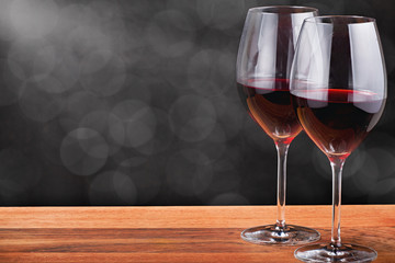 two glasses with dark red wine on wood