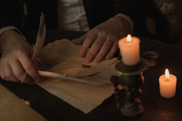 Men's hands hold a pen, want to write a letter, a candle is burning next to it