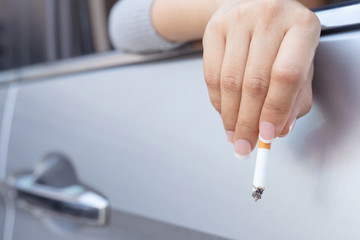 close up woman hand hold smoking a cigarette in car while driving travel.