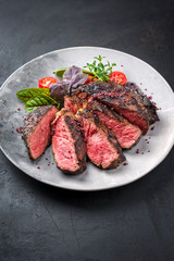 Barbecue dry aged wagyu entrecote beef steak with lettuce and tomatoes as closeup on a modern design plate