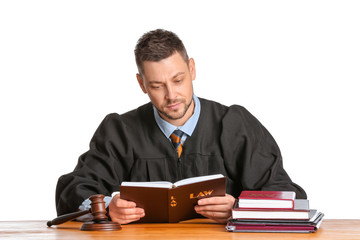 Male judge reading book at table on white background