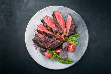 Gegrilltes dry aged Wagyu Entrecote Steak vom Rind mit Salat und Tomaten als Draufsicht auf einem...