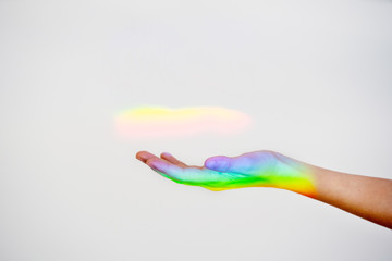 Unrecognizable woman hand with a rainbow iconic reflection on the background. Horizontal view of gay price colors reflected on a hand isolated on white background. Sexual orientation concept.