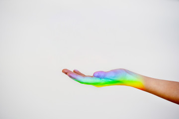 Horizontal view of gay pride colors reflected on a hand isolated on white background. Sexual orientation concept. Unrecognizable woman hand with a rainbow iconic reflection on the skin.