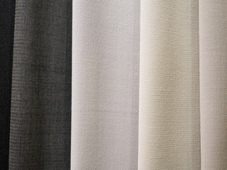 Samples of knitted fabrics in pastel light colors, in the store close-up. Trend monochrome for sewing designer clothes. A smooth transition of color