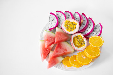 White plate of sliced fruit. Fresh fruits and vitamins. Still life colored summer fruits.