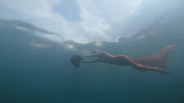Beautiful woman in red dress diving underwater