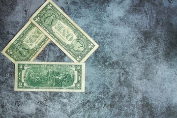 Dollar bills are stacked in the form of a house on a gray background. The concept of a mortgage for housing construction. Free space for text.