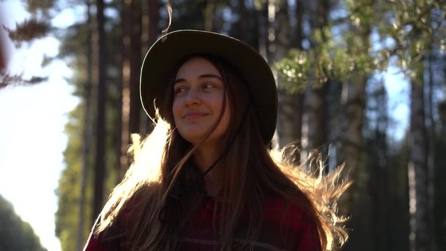 4k side view of young stylish hipster female in hat and checked shirt sits in a tent in the woods in nature on camping trip and check map, email, social networks, looks at the phone and takes selfie