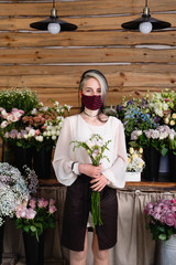 Fototapeta premium small business work concept during pandemic and quarantine. Young woman small business representative wearing a medical protective mask.