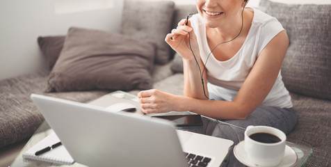 Attractive happy young student studying online at home, using laptop computer, headphones, having video chat, waving. Remote work, distance education. Video conference or virtual event on quarantine