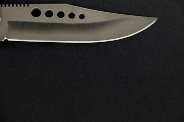 Closeup photo of a shiny and sharp hunter knife on the black background.