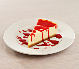 Cheesecake with strawberry syrup on white plate