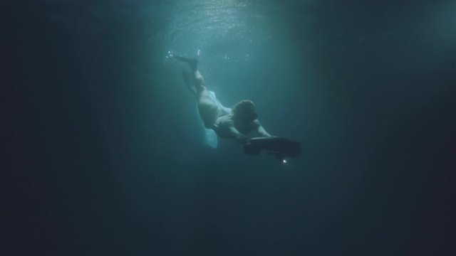 Beautiful lady swimming and diving underwater with seabob