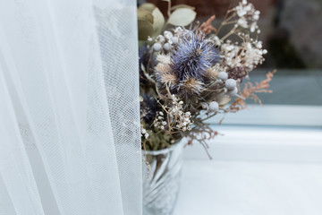 dry bouquet of flowers on a white background near the window
