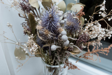 Naklejka premium dry bouquet of flowers on a white background near the window