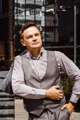 Handsome man in sunlight. Man on cityscape and buildings with reflections of city. Businessman in vest.