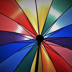 Multicolored umbrella illuminated by the sun. Bright colors, blue, green, yellow, red.
