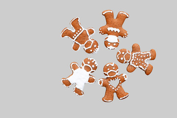 Creative gingerbread concept in coronavirus (COVID-19) time - group of gingerbread men with protective face masks, isolated on light background, copy space for text