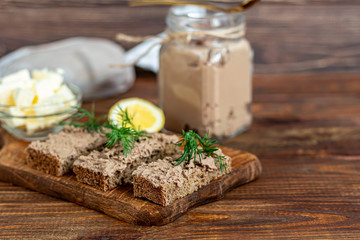 Fresh homemade chicken liver pate with carrots, onions and butter. Garnished with a sprig of dill. Lubricated on bread. On a wooden background.