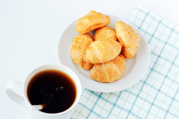 Mini croissants and cup of coffee on white background.