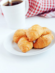 Mini croissants and cup of coffee on white background.