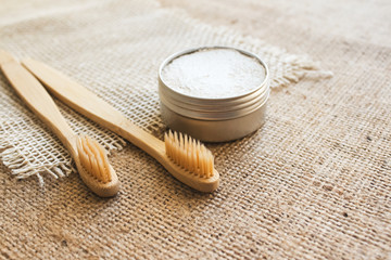 Two natural bamboo toothbrushes and kaolin dentifrice on rustic burlap background with copy space....