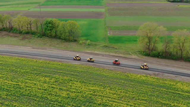 Roller machines make new asphalt roads. The asphalt paver squeezes hot asphalt.